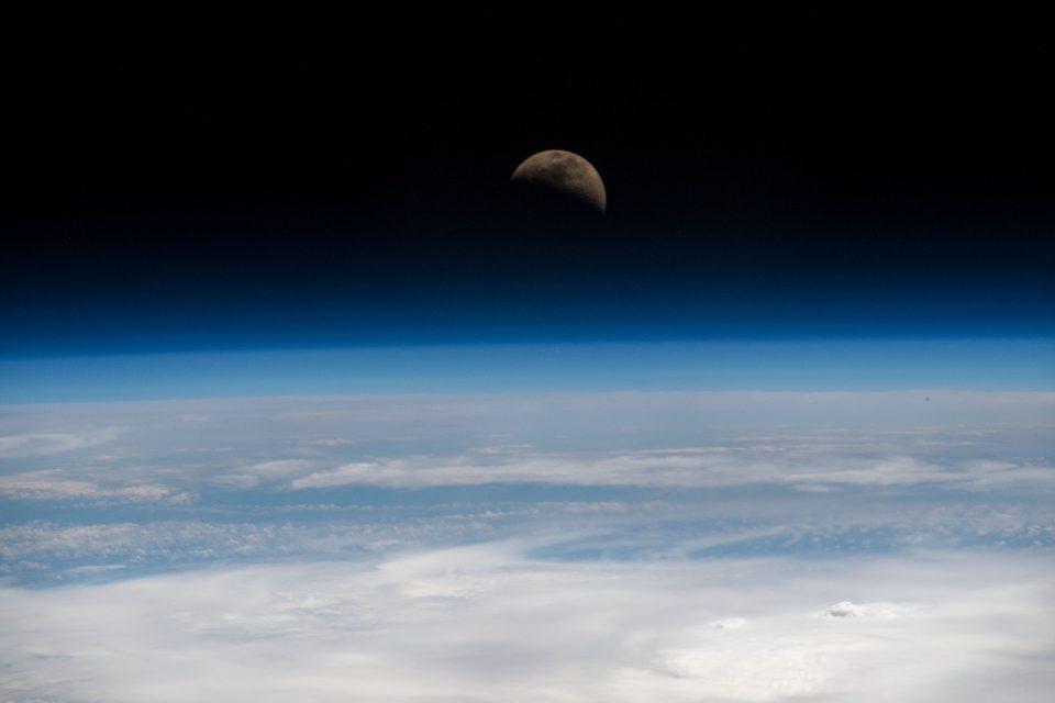 The moon hovers at the edge of the Earth's horizon