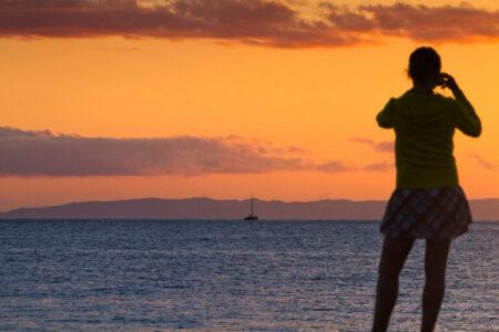 Photographer at sunset with island of Niihau in background.